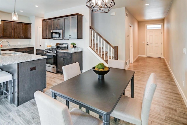 dining room with an inviting chandelier, sink, and light hardwood / wood-style flooring