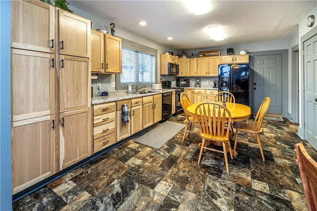 kitchen with light stone countertops, sink, light brown cabinetry, and black appliances