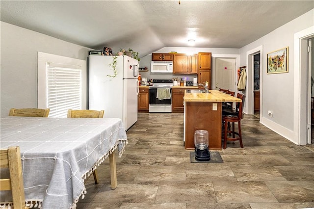 kitchen featuring a kitchen bar, sink, vaulted ceiling, tile counters, and white appliances