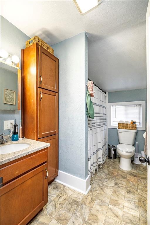 bathroom with walk in shower, vanity, toilet, and a textured ceiling