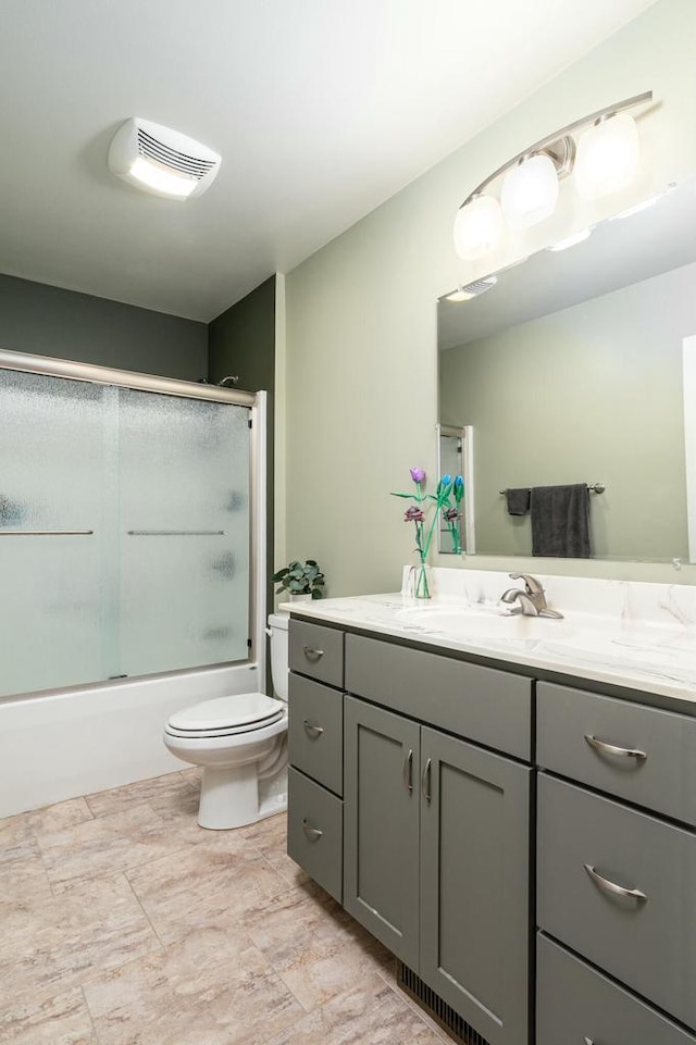 full bathroom featuring vanity, bath / shower combo with glass door, and toilet