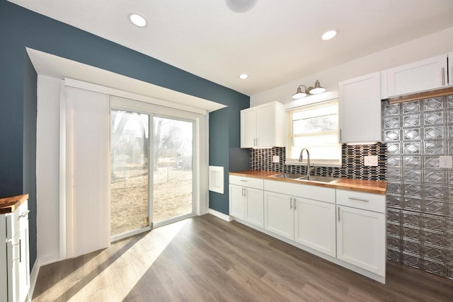 kitchen featuring white cabinetry, wooden counters, sink, and backsplash