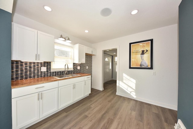 kitchen featuring white cabinetry, butcher block counters, sink, and tasteful backsplash