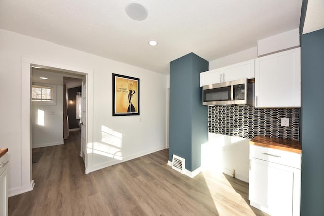 kitchen with backsplash, butcher block countertops, light hardwood / wood-style flooring, and white cabinets