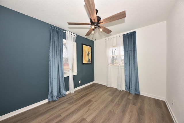 spare room with dark wood-type flooring, a textured ceiling, and ceiling fan