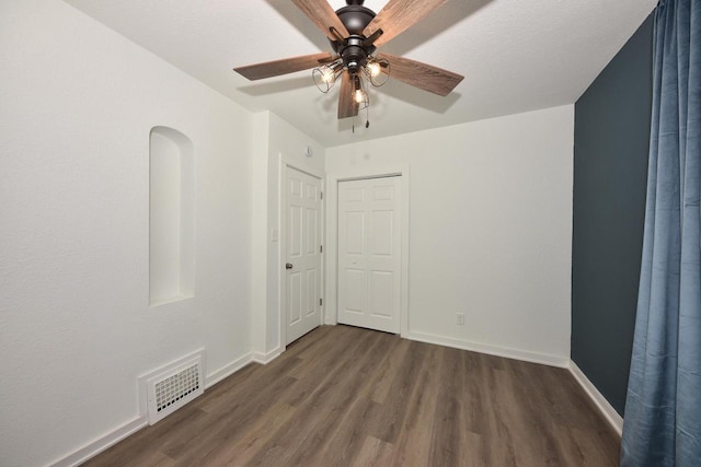 empty room featuring dark wood-type flooring and ceiling fan