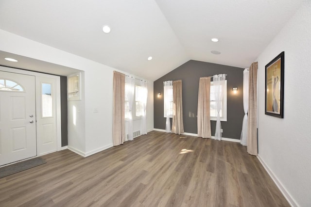 entrance foyer with lofted ceiling, dark hardwood / wood-style flooring, and a wealth of natural light