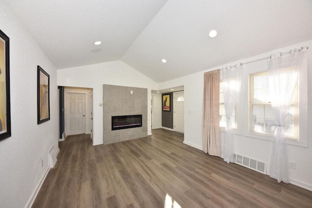 unfurnished living room featuring a tile fireplace, vaulted ceiling, and dark wood-type flooring