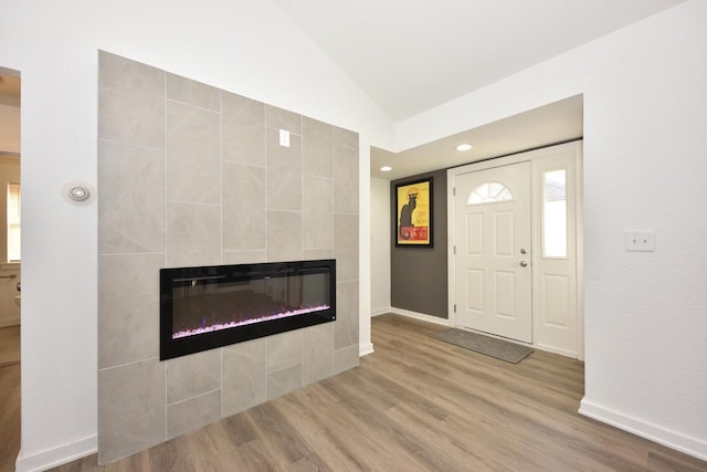 foyer with a fireplace, hardwood / wood-style flooring, and vaulted ceiling