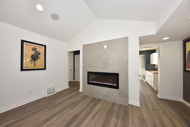 unfurnished living room featuring dark hardwood / wood-style flooring, high vaulted ceiling, and a tile fireplace