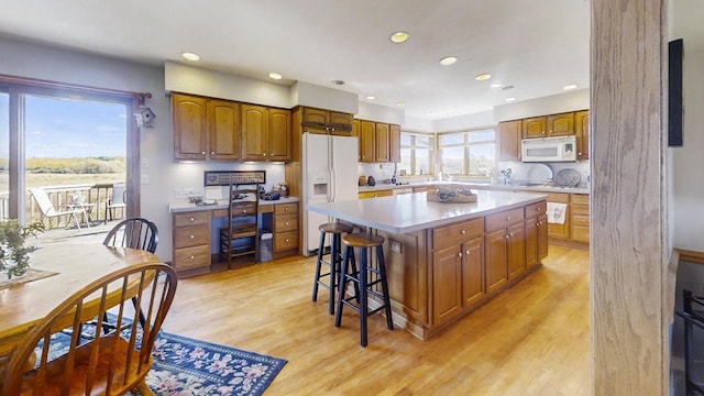 kitchen featuring a kitchen bar, white appliances, light hardwood / wood-style flooring, and a kitchen island