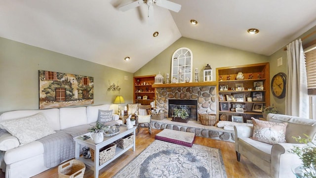 living room with lofted ceiling, hardwood / wood-style flooring, a stone fireplace, and ceiling fan