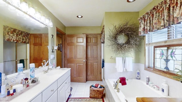 bathroom featuring tile patterned floors, vanity, and tiled bath