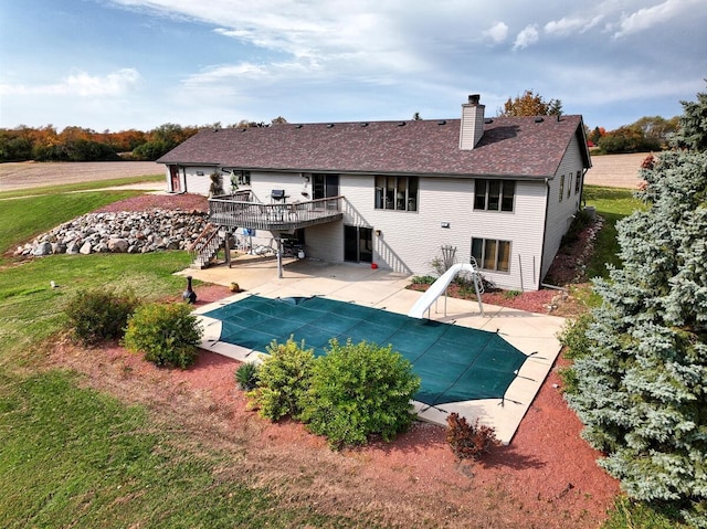 view of pool featuring a wooden deck, a water slide, a patio area, and a lawn