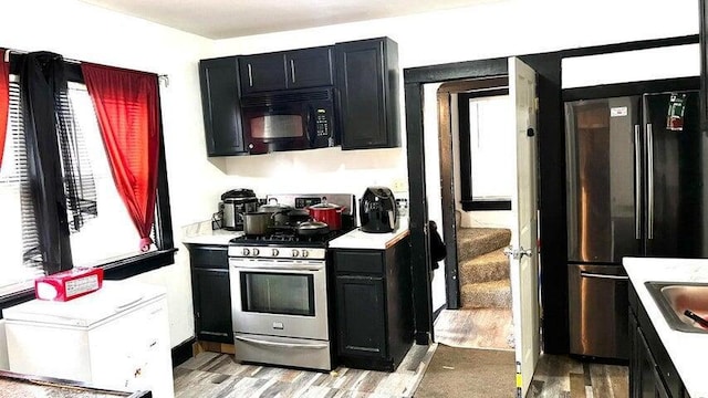 kitchen with appliances with stainless steel finishes, sink, and light wood-type flooring