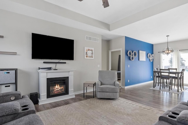 living room with ceiling fan with notable chandelier and hardwood / wood-style floors