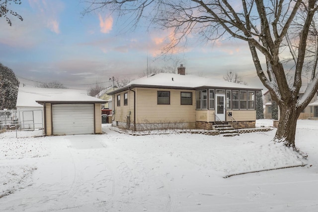 view of front of property with a garage, a sunroom, and an outdoor structure