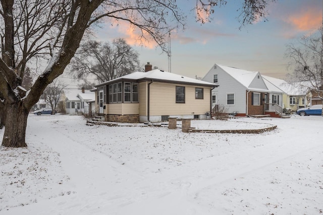 snow covered back of property with a sunroom