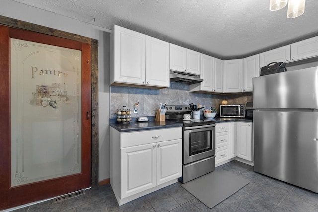 kitchen with white cabinetry, a textured ceiling, appliances with stainless steel finishes, dark tile patterned floors, and backsplash