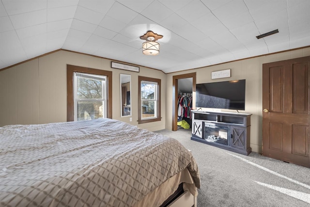 bedroom featuring vaulted ceiling, wood walls, a spacious closet, light carpet, and a closet