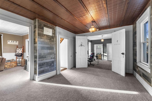 carpeted spare room featuring wood ceiling, crown molding, and wood walls