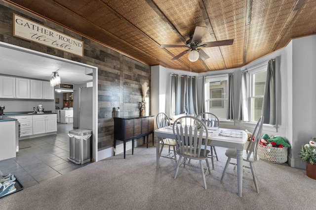 carpeted dining space with ceiling fan, separate washer and dryer, wooden ceiling, and wooden walls