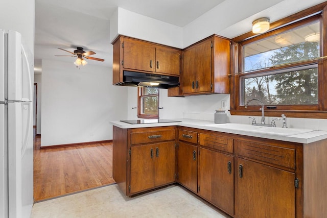 kitchen with sink, kitchen peninsula, white fridge, ceiling fan, and black electric stovetop