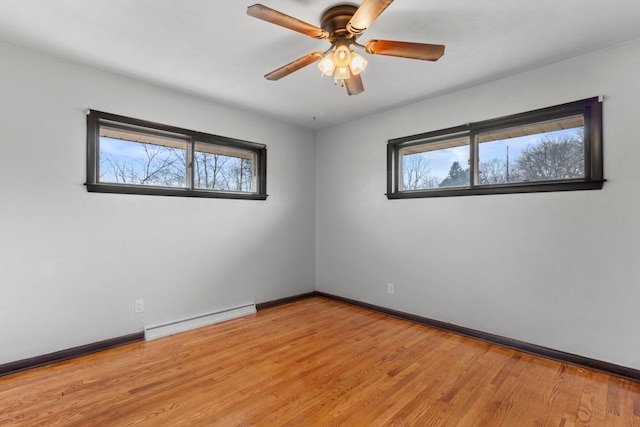 unfurnished room with baseboard heating, ceiling fan, a wealth of natural light, and light wood-type flooring