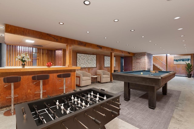 rec room with bar, pool table, concrete floors, and wood walls