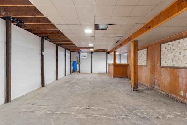 basement with a drop ceiling and wood walls