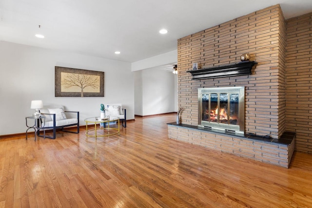 living room with ceiling fan, a fireplace, and hardwood / wood-style floors