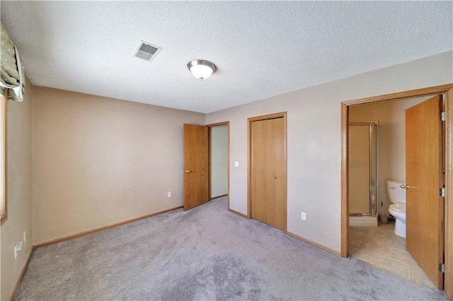 unfurnished bedroom featuring connected bathroom, light colored carpet, a closet, and a textured ceiling