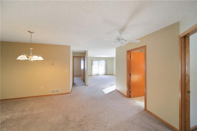 empty room with ceiling fan with notable chandelier, light carpet, and a textured ceiling