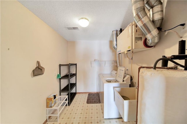 washroom with sink, washer and clothes dryer, and a textured ceiling