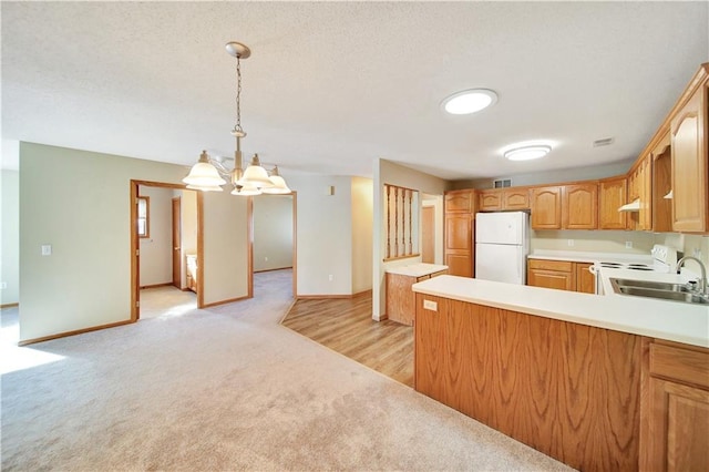 kitchen featuring sink, white appliances, decorative light fixtures, light colored carpet, and kitchen peninsula