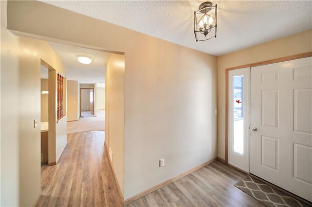 foyer entrance with light hardwood / wood-style floors and a textured ceiling