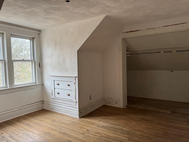 additional living space featuring vaulted ceiling and light hardwood / wood-style flooring