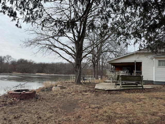 view of yard featuring a deck with water view and an outdoor fire pit