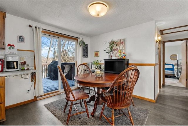 dining space with dark wood-type flooring and a textured ceiling