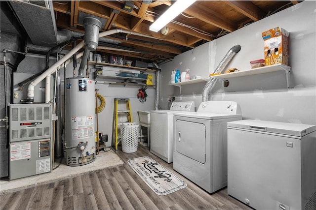 washroom with heating unit, hardwood / wood-style floors, washing machine and dryer, and water heater