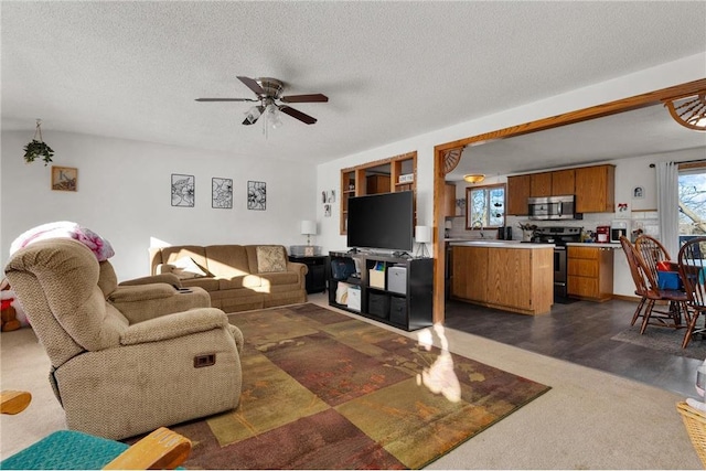 living room featuring sink, a textured ceiling, plenty of natural light, and ceiling fan