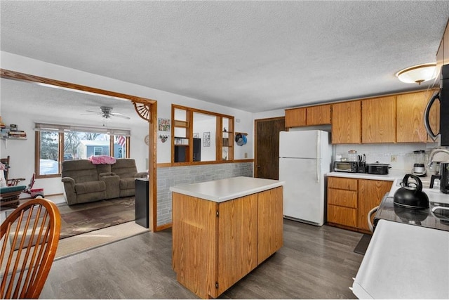 kitchen with white refrigerator, a center island, dark wood-type flooring, and a textured ceiling