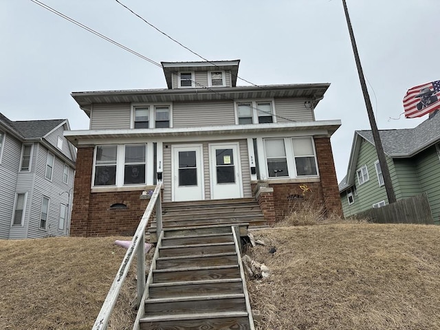 american foursquare style home with entry steps, fence, and brick siding