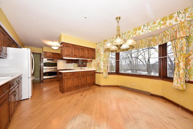 kitchen with pendant lighting, light hardwood / wood-style flooring, baseboard heating, double oven, and a notable chandelier