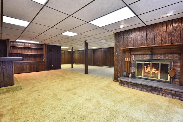 basement with a baseboard radiator, a brick fireplace, carpet floors, and wooden walls