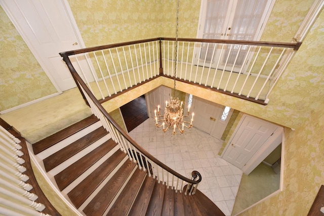 stairway featuring a towering ceiling and a chandelier