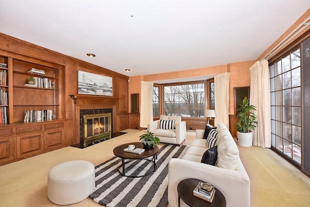 carpeted living room with a high end fireplace, built in features, and a healthy amount of sunlight