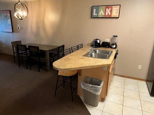 kitchen featuring a breakfast bar, pendant lighting, sink, a chandelier, and light tile patterned floors