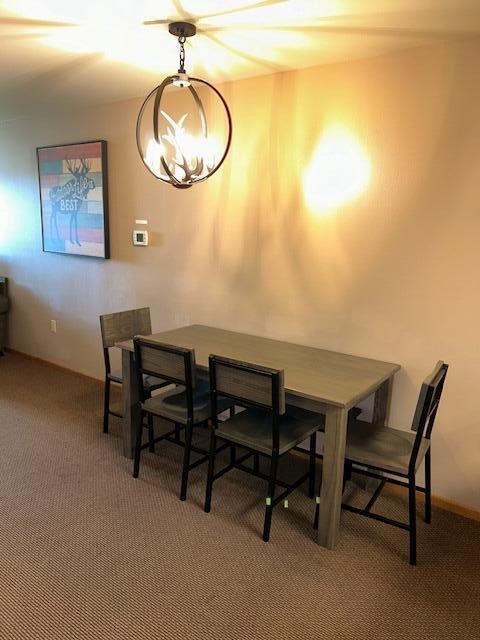 carpeted dining space featuring a chandelier