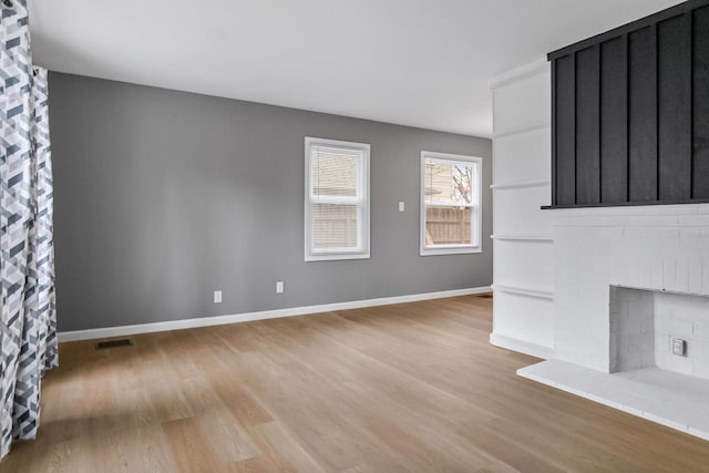 unfurnished living room featuring a fireplace and light hardwood / wood-style flooring